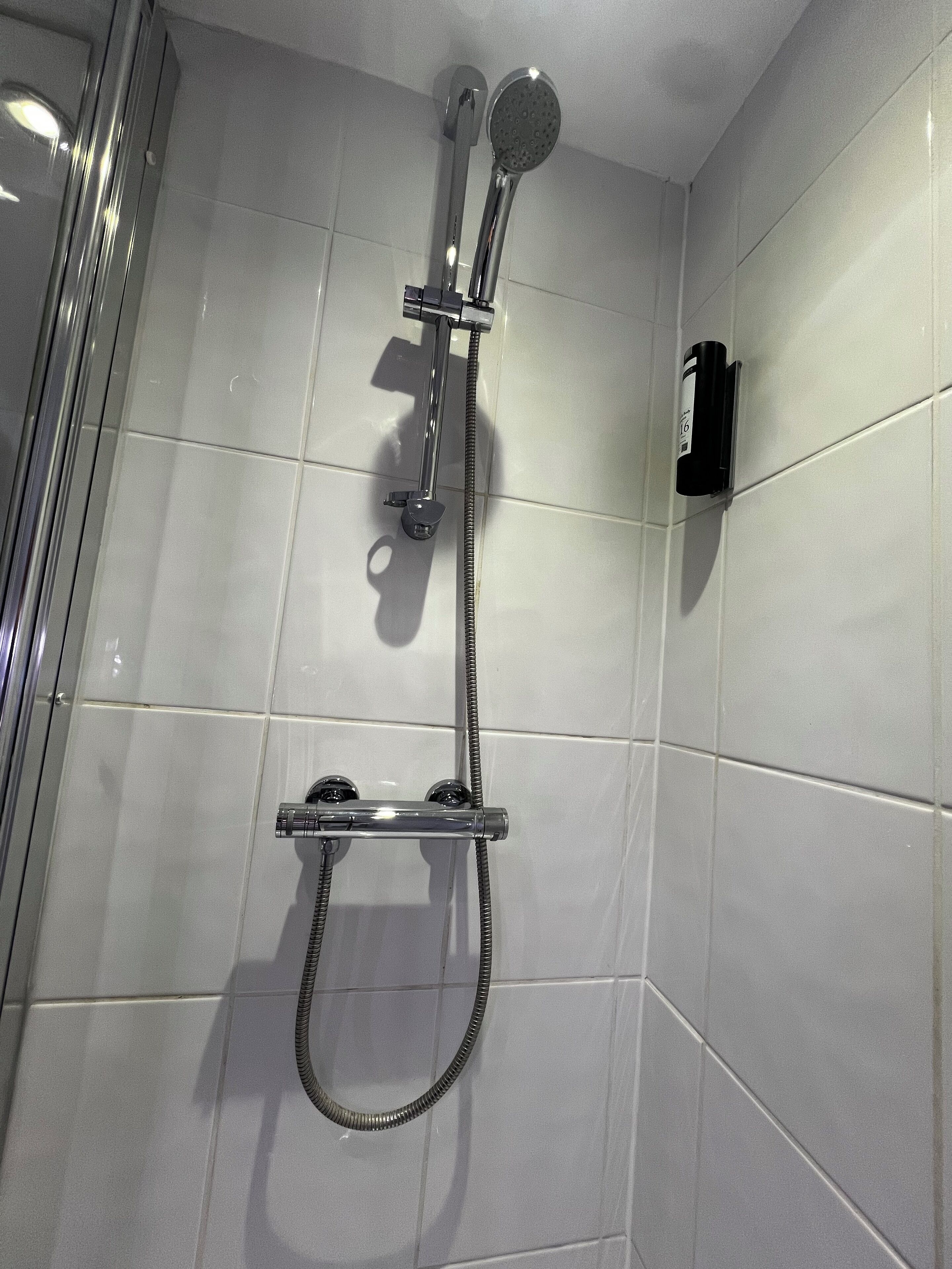 A shower with a handheld showerhead and a fixed showerhead, both mounted on a wall.