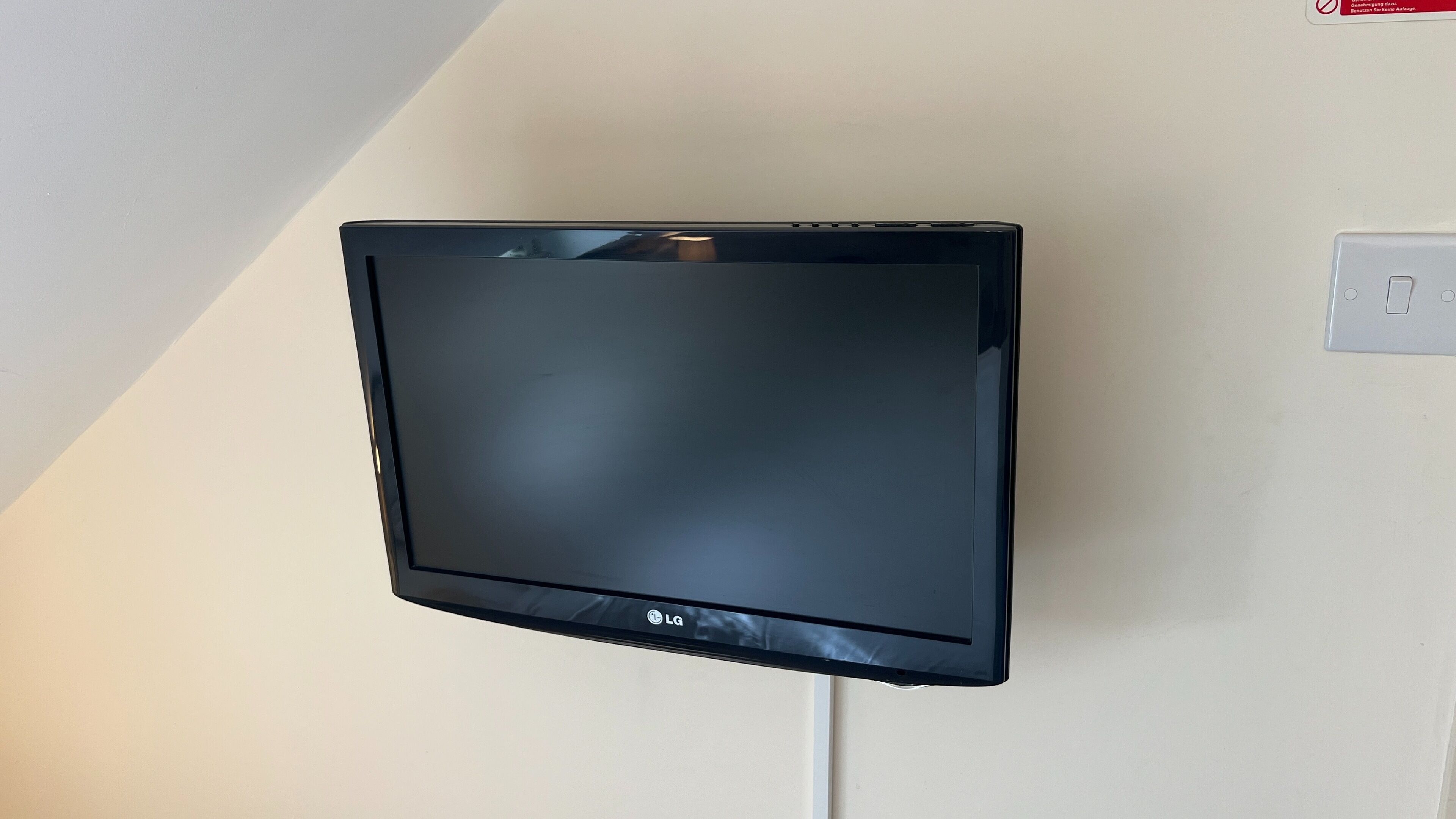 A flat-screen TV mounted on a wall with a power outlet nearby.