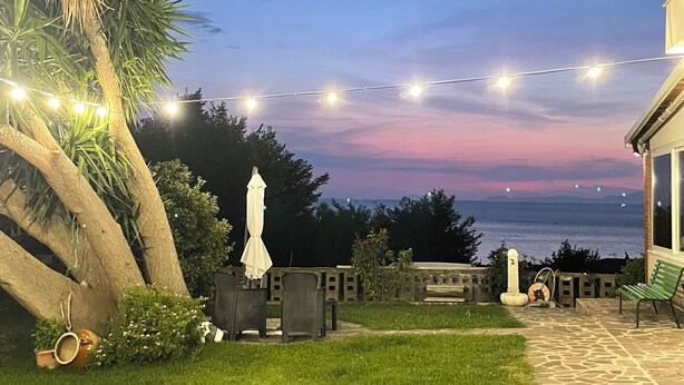 A patio area with string lights, outdoor furniture, and a view of the sea at dusk. - Beb sunset da Carla  (Agropoli)