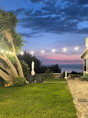 A patio area with string lights, outdoor furniture, and a view of the sea at dusk. - Beb sunset da Carla  (Agropoli)