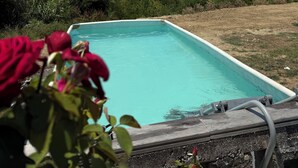 A rectangular pool with clear blue water, surrounded by greenery and a view of the sea. - Beb sunset da Carla  (Agropoli)
