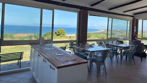 A kitchen with a view of the sea, large windows, and a dining area with chairs. - Beb sunset da Carla  (Agropoli)