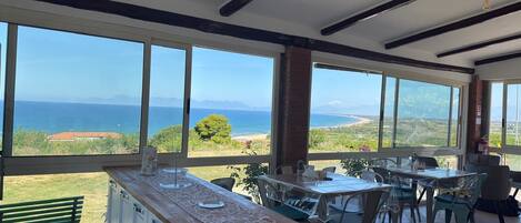 Una cocina con vista al mar, ventanas amplias y un comedor con sillas.