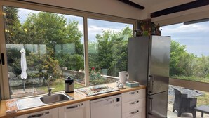 A modern kitchen with a large window, a stainless steel refrigerator, and a dining area with a table and chairs. - Beb sunset da Carla  (Agropoli)