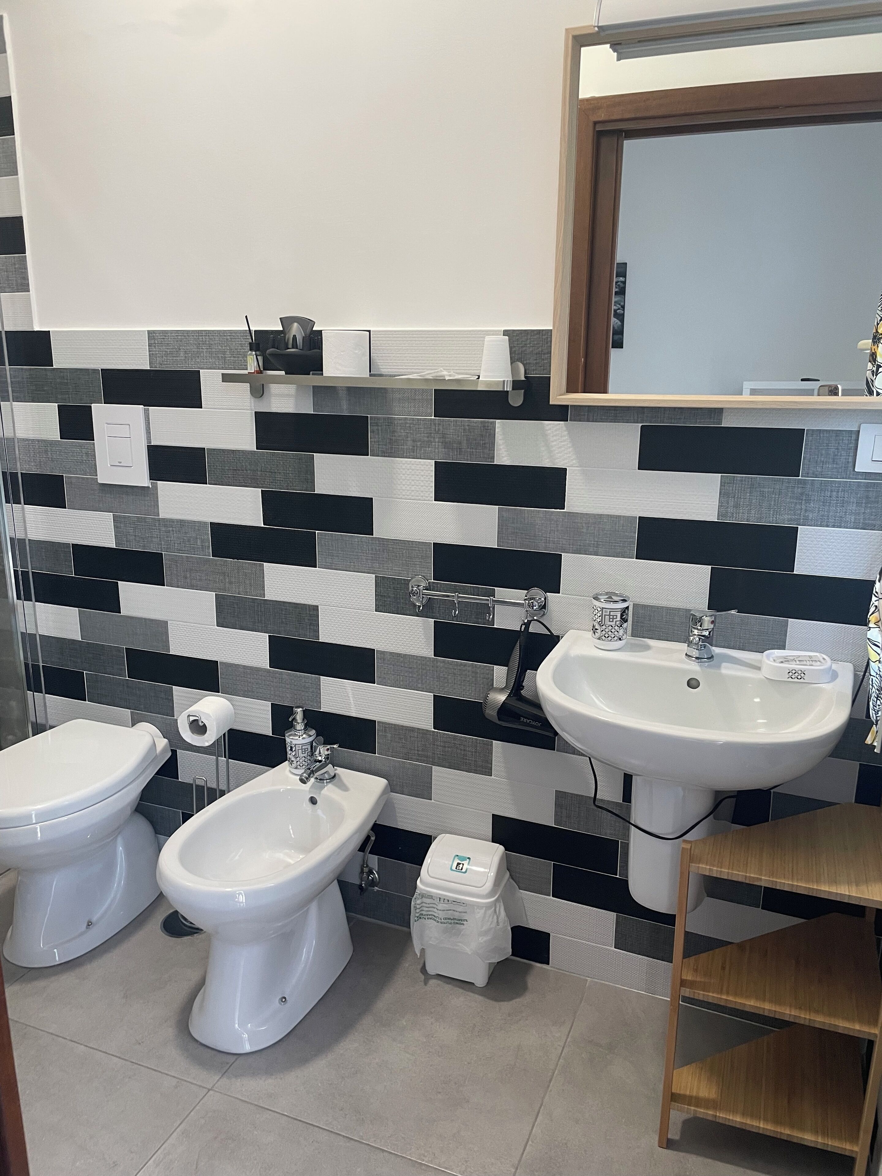 A bathroom with two bidets, a sink, and a mirror.