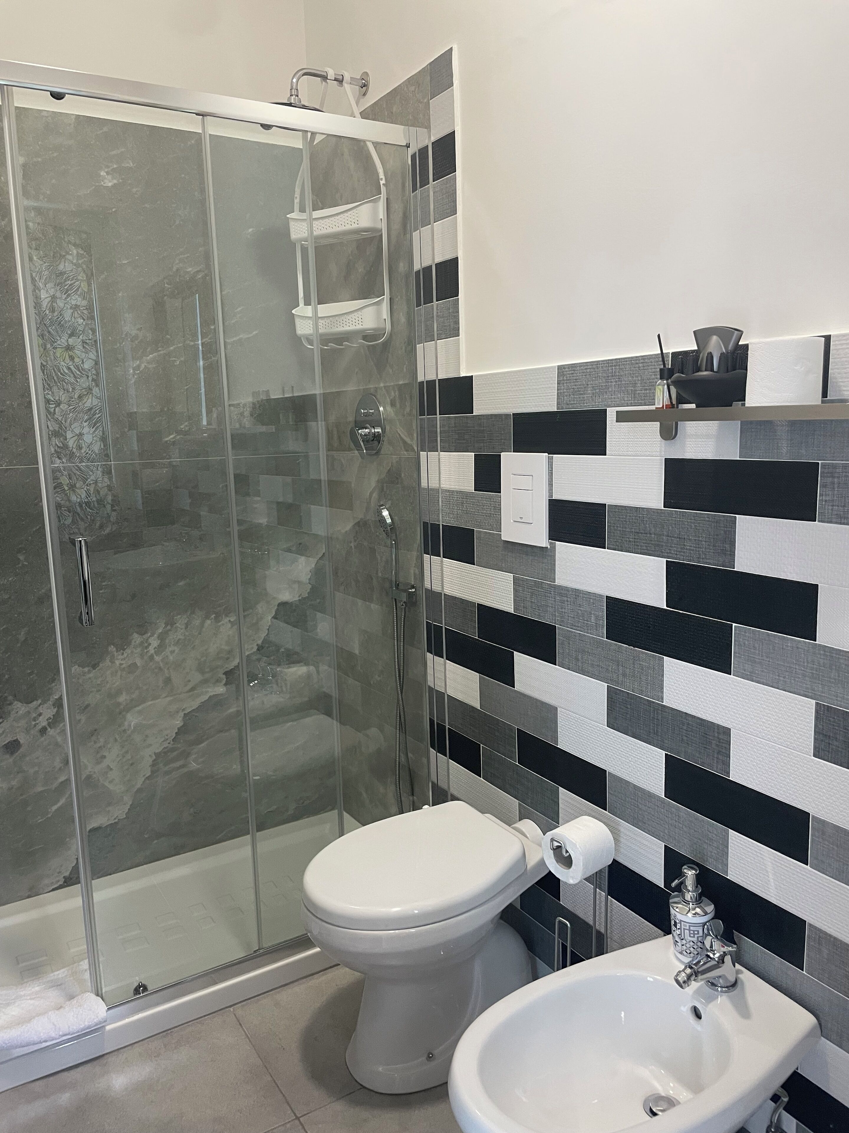 A modern bathroom with a glass-enclosed shower, a toilet, and a sink.