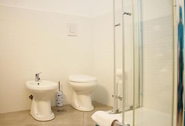 A bathroom with two toilets, a bidet, and a glass shower enclosure. - Beb sunset da Carla (Agropoli)