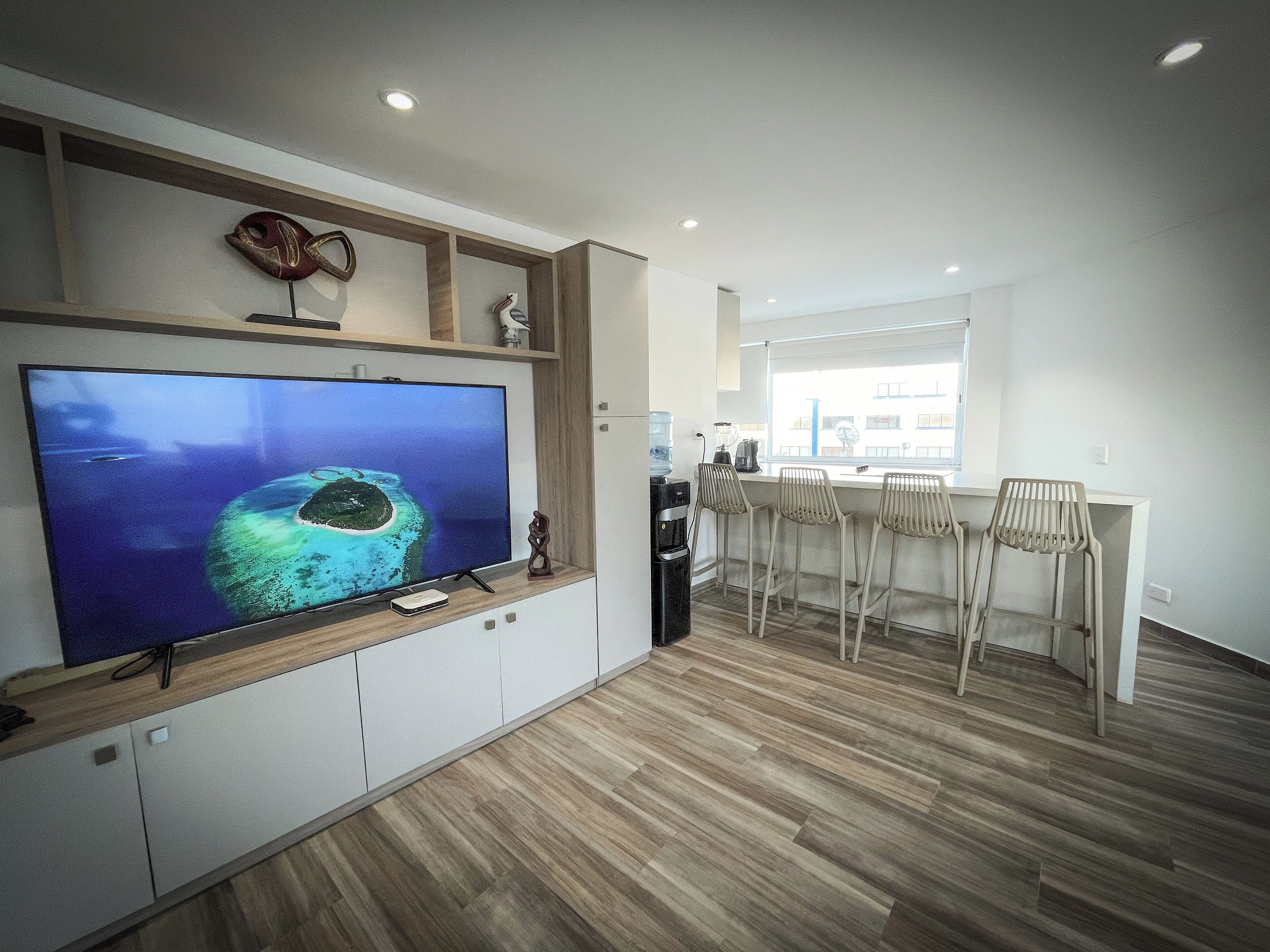 Una cucina moderna con un grande schermo piatto, mobili in legno e un'area bar con sgabelli.
