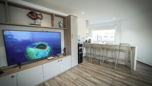 Eine moderne Küche mit einem großen Flachbildfernseher, Holzschränken und einer Bar mit Hockern.