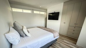 Ein Schlafzimmer mit Bett, Kissen, Fernseher und Kleiderschrank.