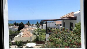 A coastal view from a balcony with a clear sky, a tiled roof, and a garden with red flowers. - Villa Marina Sea-Views with Private Pool (Peyia)