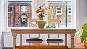 A dining table with two chairs and a vase with flowers. - Bright & Stylish Flat in the Heart of Islington (London)