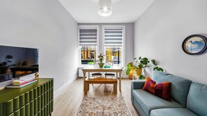 A modern living room with a TV, sofa, and a dining area with a table and chairs. - Bright & Stylish Flat in the Heart of Islington (London)