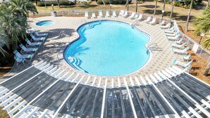 A swimming pool with a unique curved design, surrounded by a white fence and multiple lounge chairs. - Maravilla 1213 - Dog Friendly and Beach Service! (Miramar Beach)