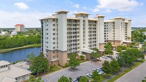 A multi-story hotel with a central courtyard, a swimming pool, and a view of a river. - Lost Key B203 (Pensacola)