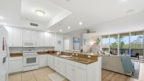 A modern kitchen with white cabinets, a granite countertop, and a built-in microwave. - Lost Key B203 (Pensacola)