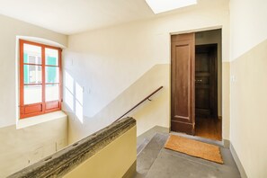 A staircase with a wooden handrail, a window with red shutters, and a door leading to another room. - San Pierino - One Bedroom Apartment, Sleeps 2 (Firenze)