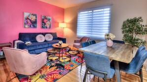 Ein Wohnzimmer mit einem blauen Sofa, einem Holzesstisch und einem farbenfrohen Teppich.