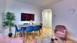 Ein modernes Wohnzimmer mit Essbereich, einem großen Fenster und einer Uhr an der Wand.