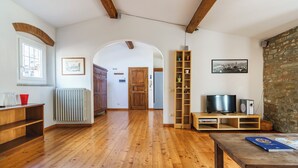 Amplia sala de estar con piso de madera, televisor y estantería.