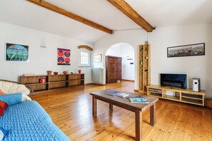A spacious living room with wooden floors, a sofa, a coffee table, and a TV stand with a flat-screen TV and speakers. - San Pier Maggiore - One Bedroom Apartment, Sleeps 2 (Firenze)