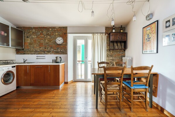 A kitchen with wooden cabinets, a washing machine, and a dining area with a table and chairs. - San Pier Maggiore - One Bedroom Apartment, Sleeps 2 (Firenze)