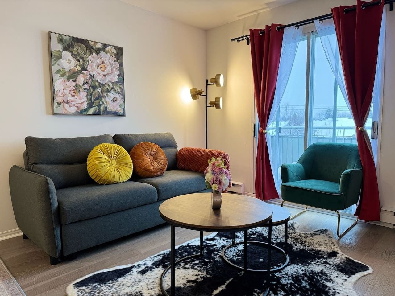 A living room with a sofa, a coffee table, a green armchair, and a painting on the wall.