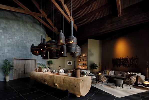 Un intérieur moderne avec une table en bois au centre, des luminaires suspendus et un mur en pierre.