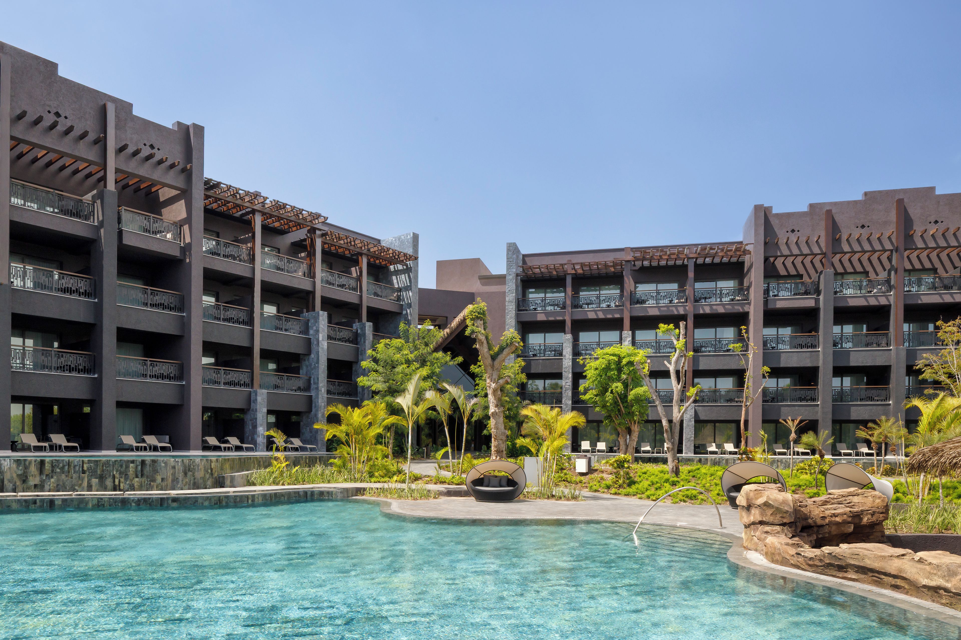 Un hôtel doté de nombreux balcons, d’une piscine et d’un aménagement paysager de style tropical.