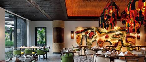 Un restaurant avec des chaises et des tables vertes, et un sol orné d’un motif géométrique.