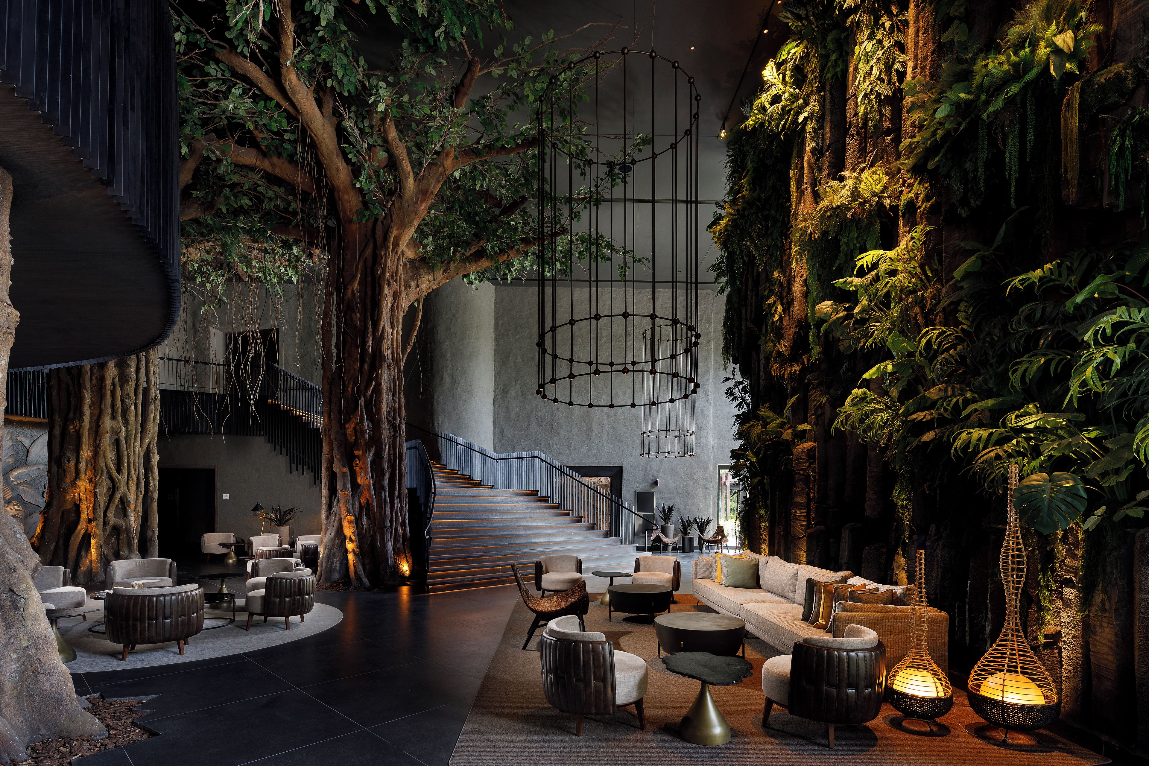 A modern interior with a central staircase, seating areas, and a wall with vertical greenery.