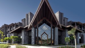 A modern building with a distinctive triangular roof structure, large windows, and a symmetrical facade. - Lopesan Serenity Bay Resort, Spa & Casino – Adults Only All-Inclusive (Punta Cana)
