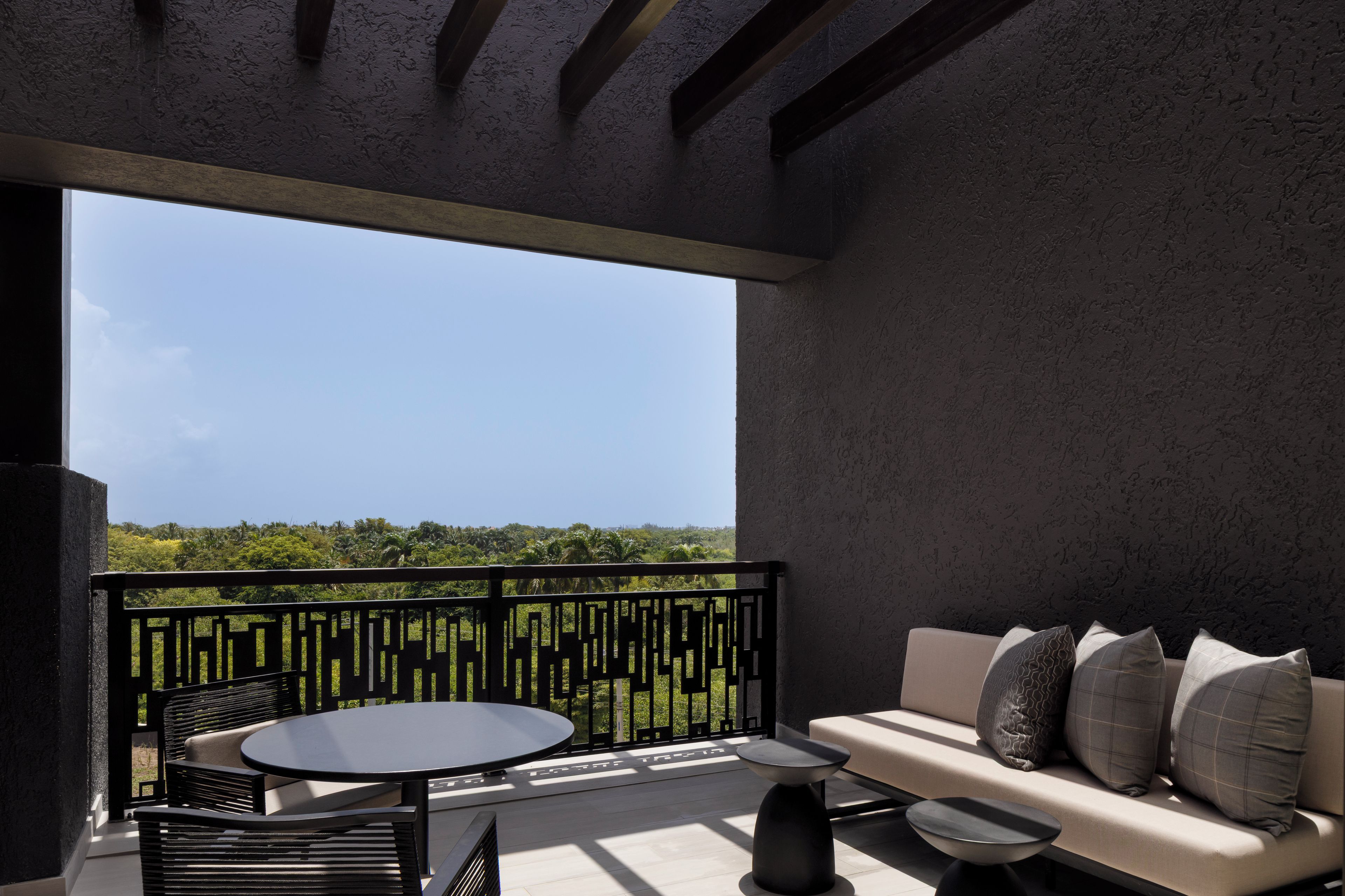 Ein Balkon mit einer Couch und einem runden Tisch, mit Blick auf eine üppige grüne Landschaft.