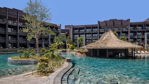 A hotel with a swimming pool, a thatched-roof structure, and a multi-story building with balconies. - Lopesan Serenity Bay Resort, Spa & Casino – Adults Only All-Inclusive (Punta Cana)