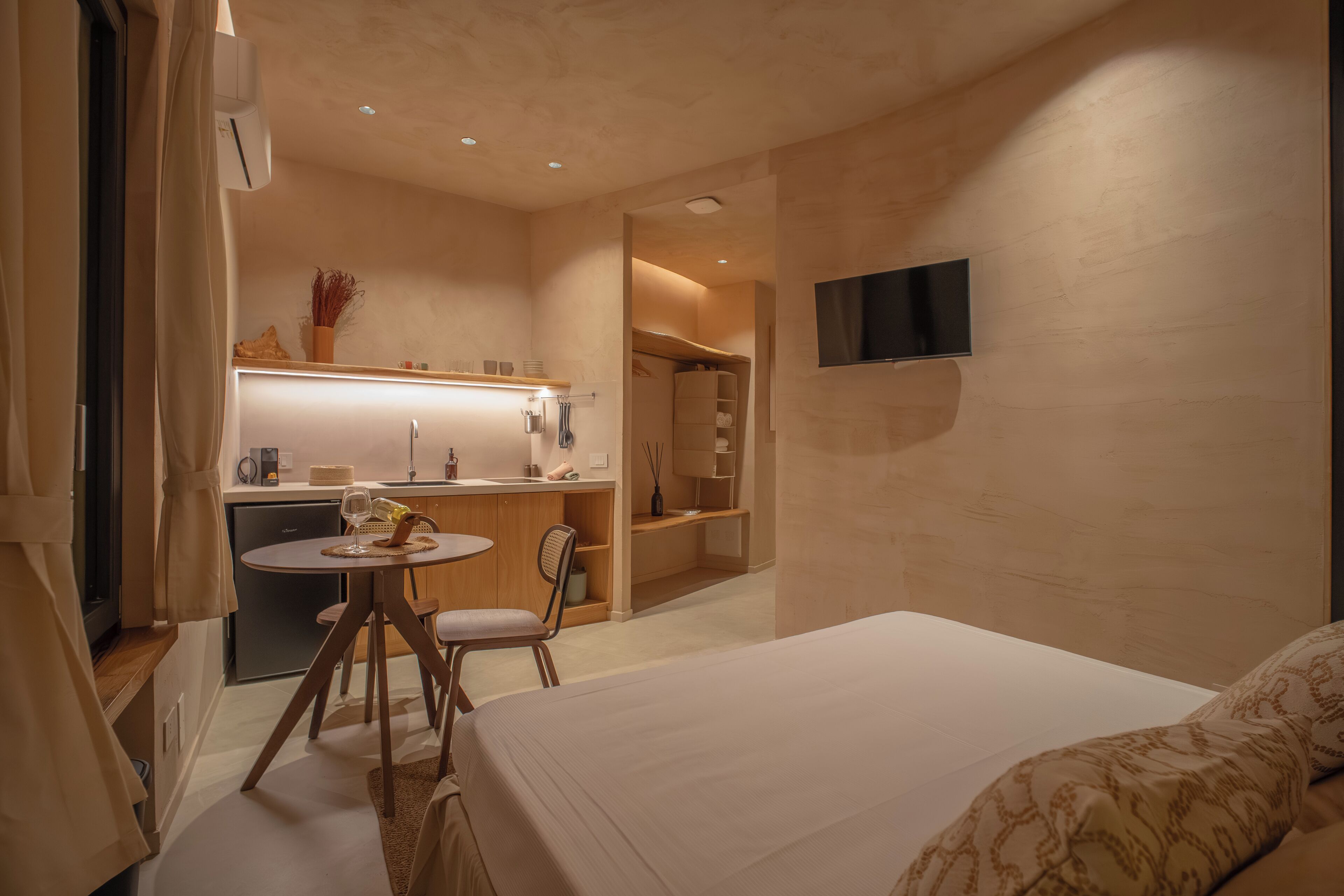Hotelkamer met een bed, een bureau en een stoel. Er is een televisie aan de muur en een raam met gordijnen.