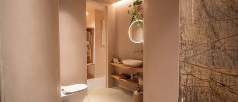 A modern bathroom with a toilet, sink, and shelves.