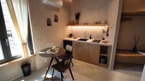 A compact kitchen with a dining area, a built-in sink, and a window with curtains. - Essenza Boutique Apartments (Cefalù)