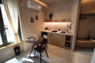 A compact kitchen with a dining area, a built-in sink, and a window with curtains.