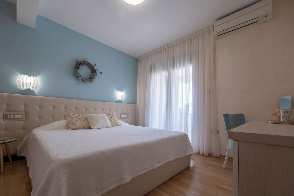 A bedroom with a large bed, a desk, and a chair.