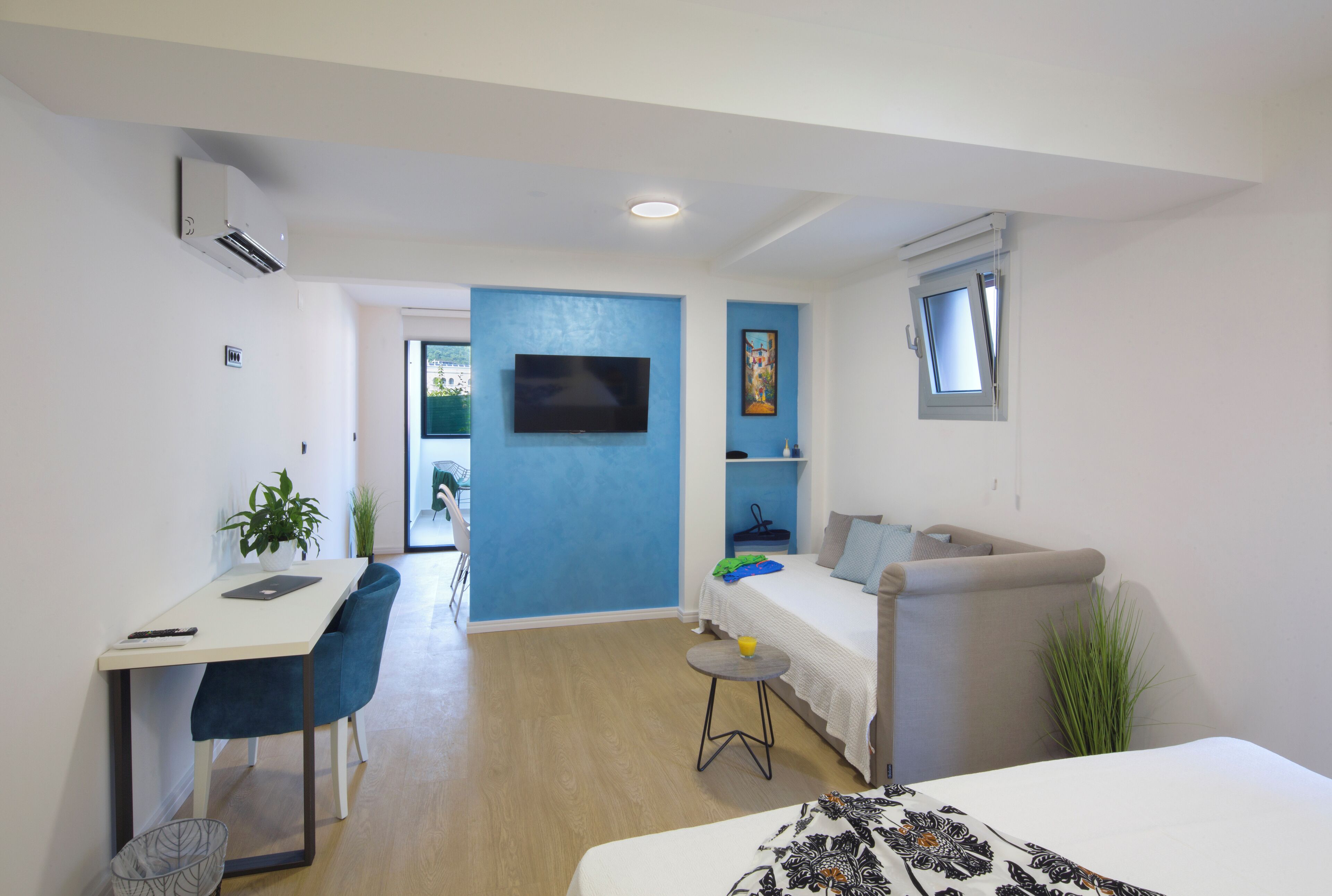 Una habitación moderna y bien iluminada con escritorio, silla, sofá y televisión.