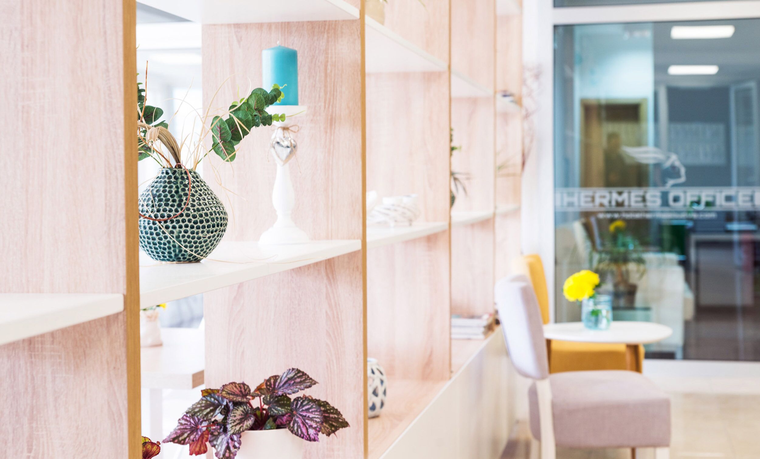 A reception area with a wooden reception desk, a blue candle, and a potted plant with variegated leaves.