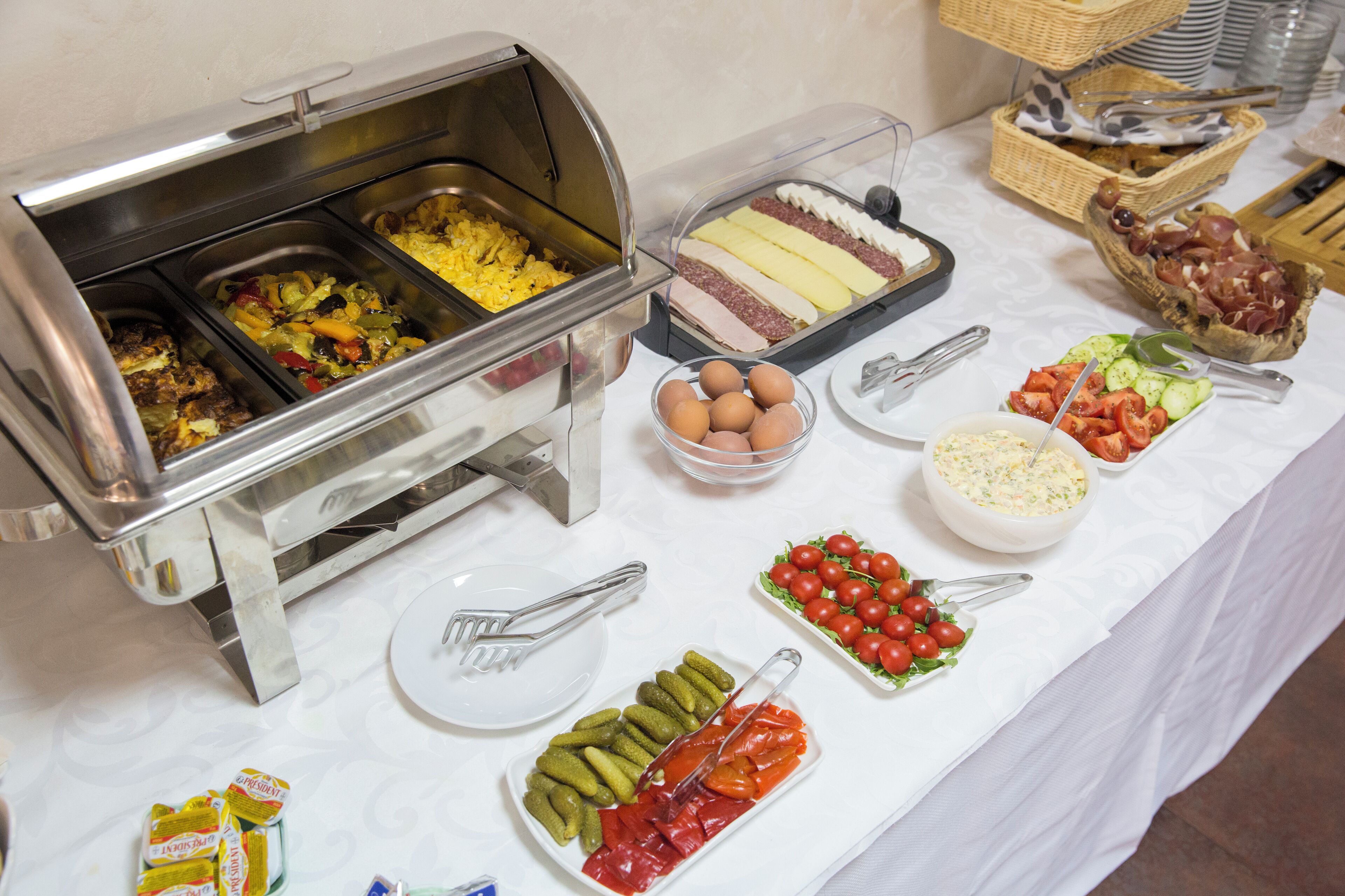 Un bufé con diferentes opciones de comida, incluyendo huevos, carnes y verduras.