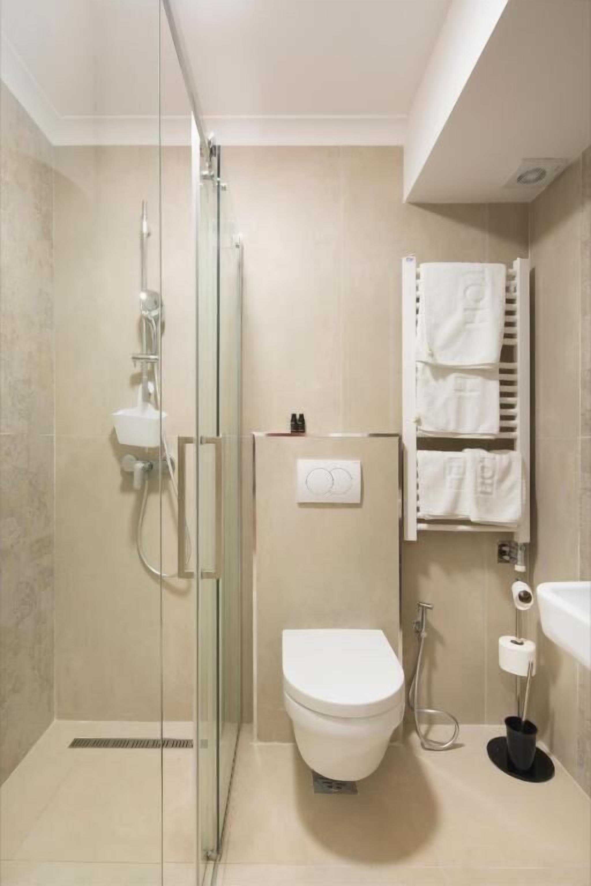 A modern bathroom with a glass shower enclosure, a toilet, and a towel rack.