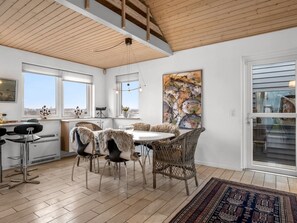 Eine moderne Küche mit Essbereich, ausgestattet mit einem großen Fenster, einem Esstisch mit Stühlen und Blick ins Freie.