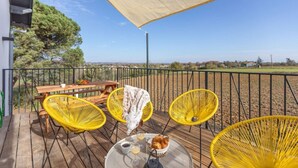 A wooden deck with yellow wicker chairs, a picnic table, and a table with drinks and pastries. - Cottage Duo Syrah Sauna Gaillac- LesCottagesduTarn (Brens)