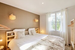 Een slaapkamer met een houten bed, twee bedlampen, een raam met gordijnen en een houten garderobe.