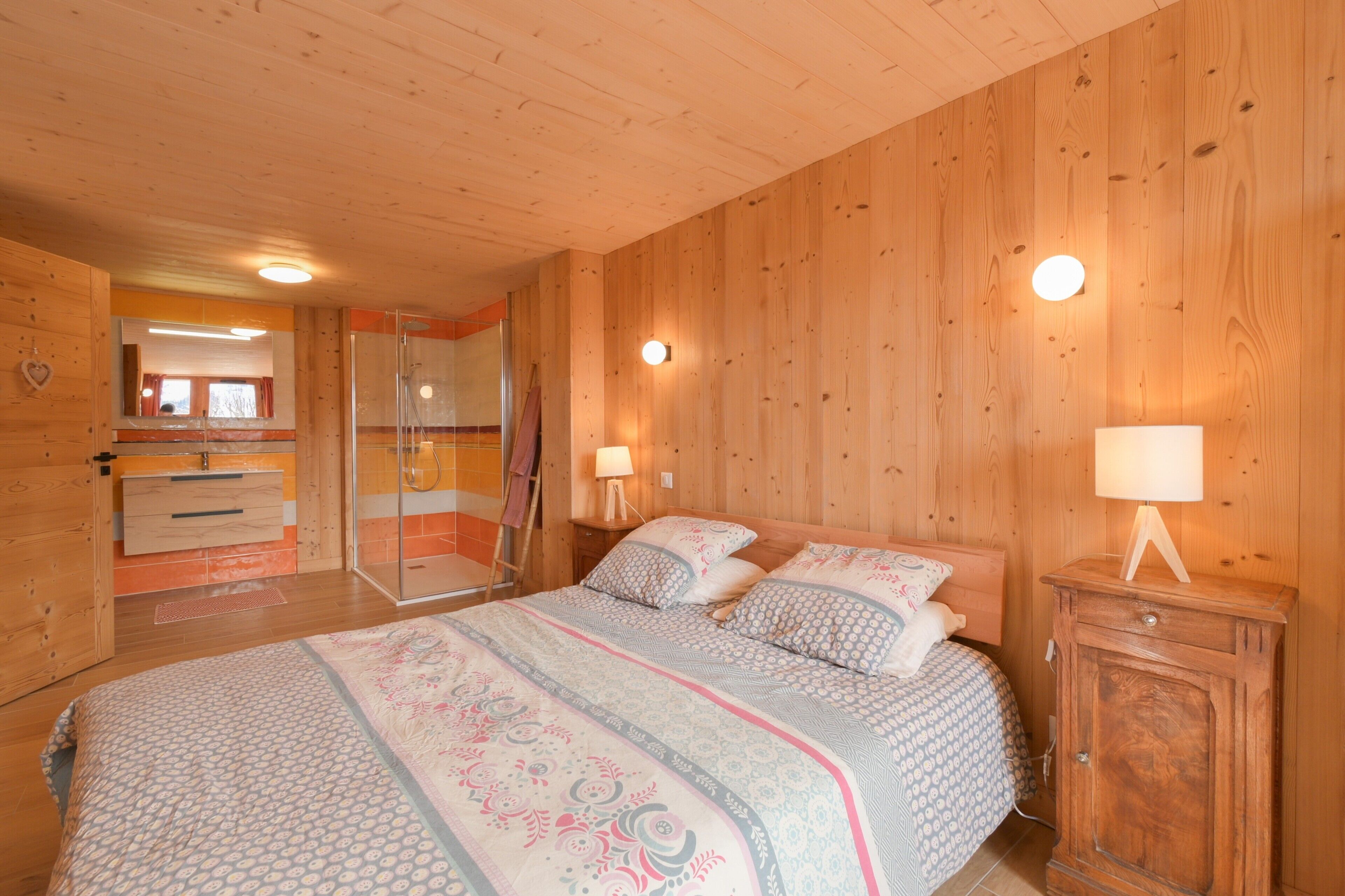 Une chambre à coucher aux murs lambrissés, avec un lit, des lampes de chevet et une armoire.