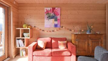 A wooden interior with a pink sofa, a bookshelf, and a wooden cabinet.