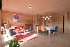 A wooden interior with a sofa, chairs, a dining table, and a bookshelf. - Apartment in Chalet L'Albert with Mountain View, Balcony, and Private Terrace (Manigod)