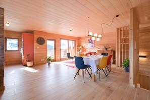 A wooden interior with a dining area, potted plants, and a view through the windows. - Apartment in Chalet L'Albert with Mountain View, Balcony, and Private Terrace (Manigod)